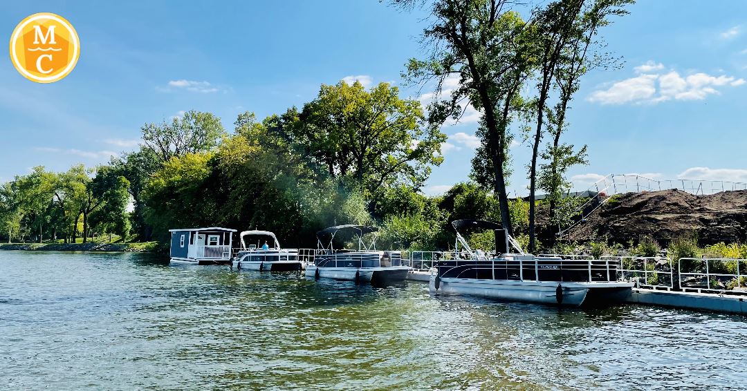 A view of the floating Your Boat Club dock, boat and rental house on the river.